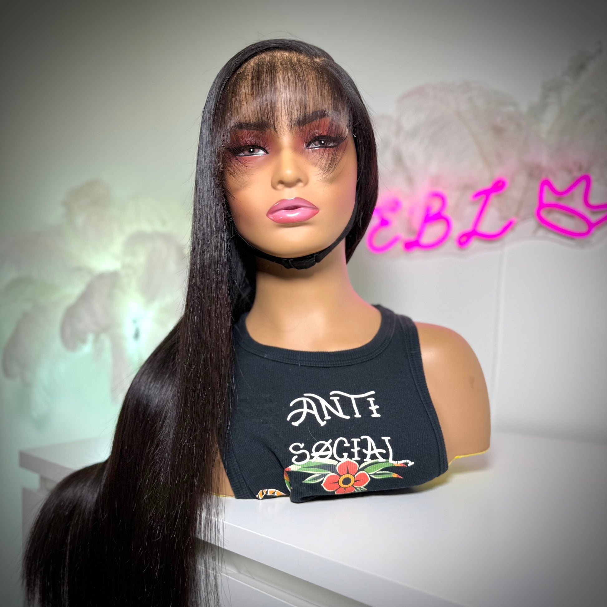 Mannequin head with long black wig and a shirt against a blurred background
