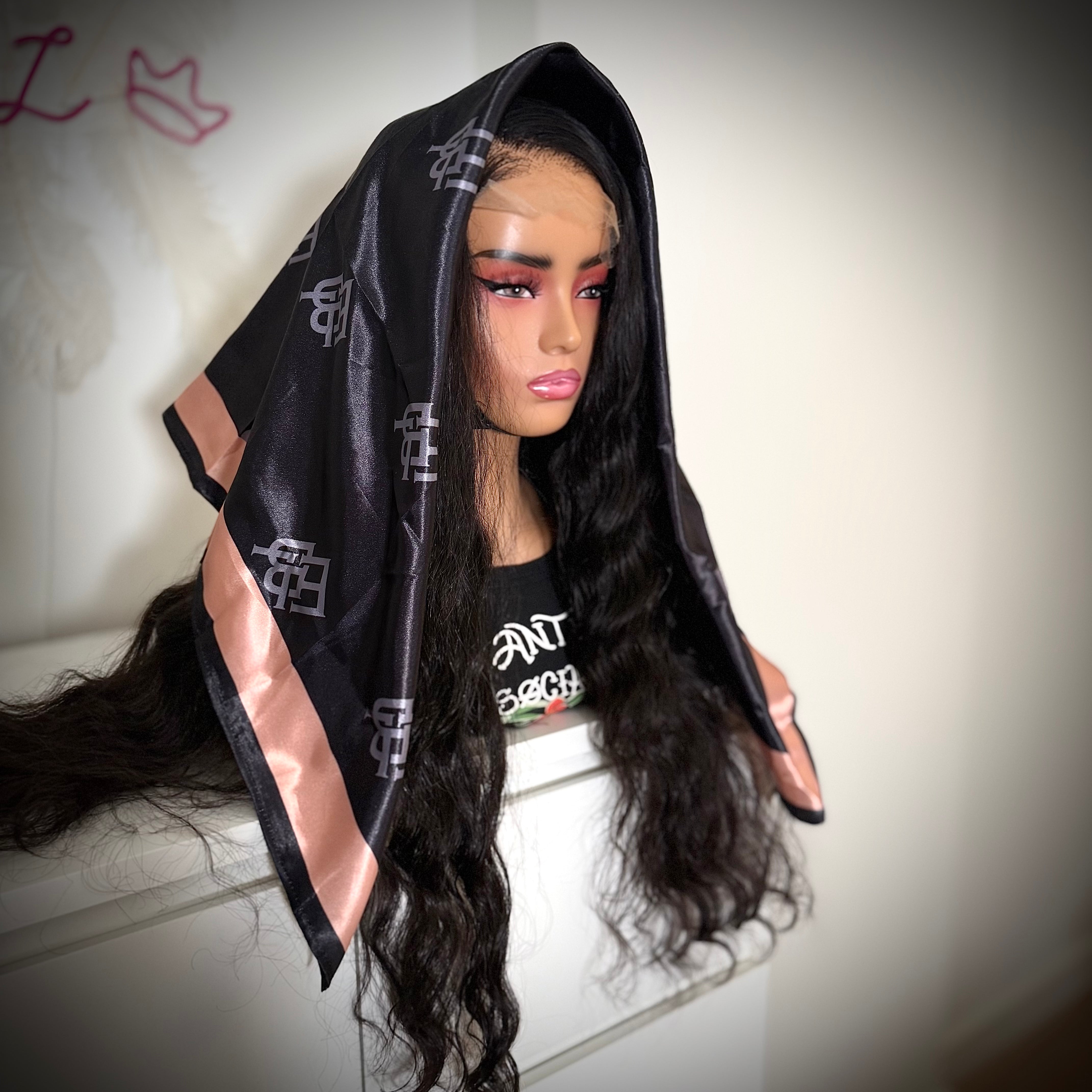 Mannequin head with a black wig draped over it, wearing a black and pink garment.