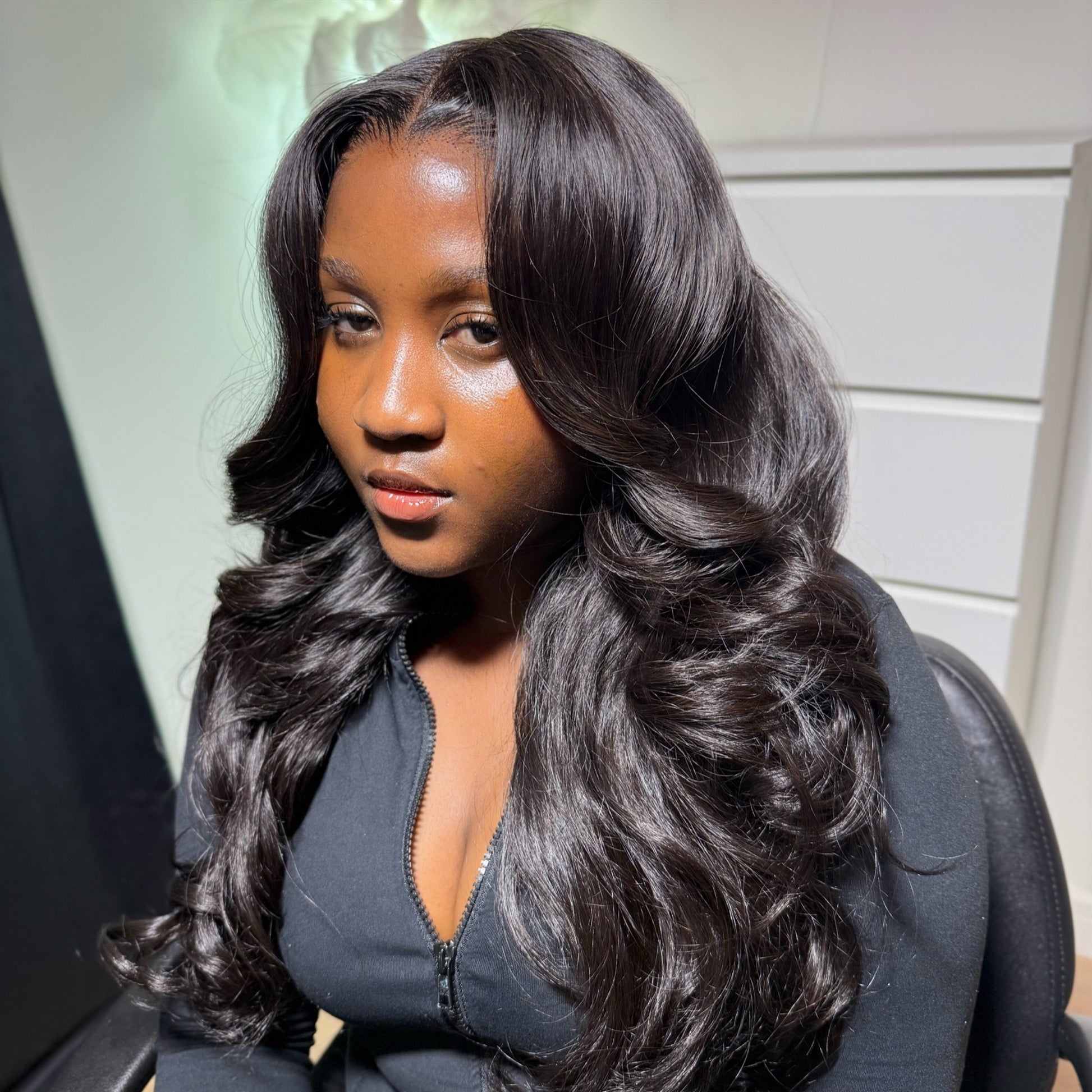Woman with long, wavy hair wearing a dark outfit.