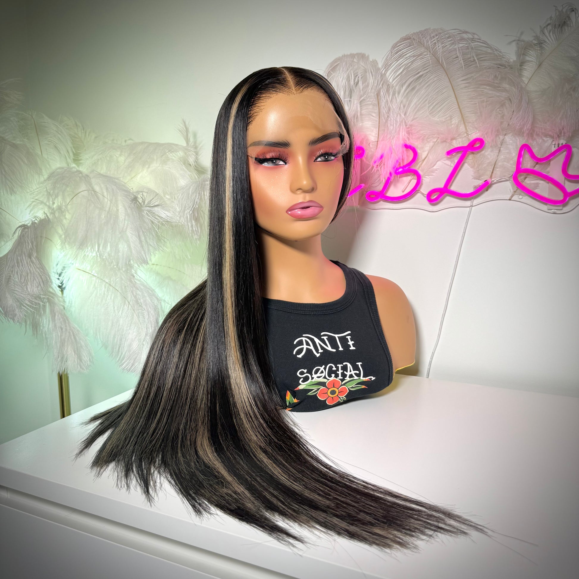 Mannequin head with long black hair and 'ANTI SOCIAL' t-shirt against a decorative background.