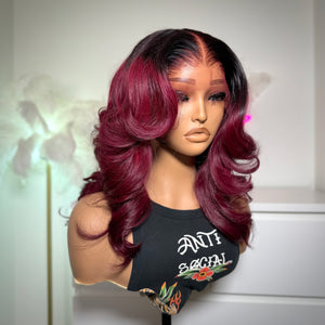 Mannequin head with a burgundy and black ombre wig on a white background