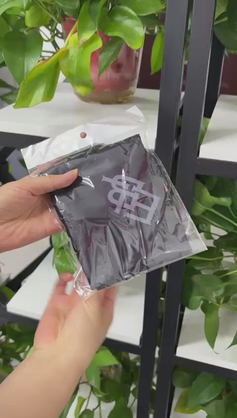 Load video: Person wearing a black headscarf with a logo, against a blurred background.